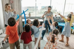 Kids and teachers having fun with bubbles and balloons in a lively classroom setting.